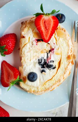 Rouleau de meringue avec des baies à la crème fouettée sur une assiette.Top veiw.selective Focus Banque D'Images