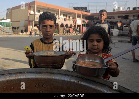 Gaza. 15 juin 2024. Des enfants palestiniens reçoivent une aide alimentaire dans la ville de Khan Younis, dans le sud de la bande de Gaza, le 15 juin 2024. Crédit : Rizek Abdeljawad/Xinhua/Alamy Live News Banque D'Images