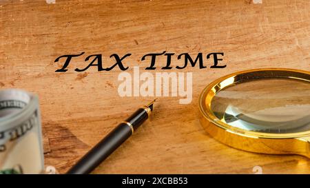 Concept commercial et fiscal. Tax Time mot sur papyrus dans une composition avec une loupe, stylo plume et dollars sans focus Banque D'Images