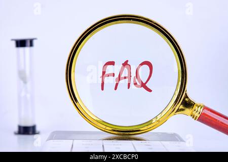 Mots FAQ. Concept de question et de réponse. FAQ écrit à travers une loupe debout sur une calculatrice dans une composition de sablier Banque D'Images