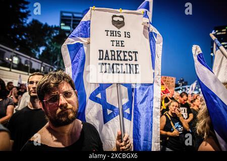 Tel Aviv, Israël. 15 juin 2024. Un manifestant tient une pancarte indiquant « C'est la chronologie la plus sombre » pendant la manifestation. Les manifestants se sont rassemblés dans des dizaines de lieux à travers Israël samedi soir pour appeler à mettre fin à la guerre à Gaza pour un accord d'otages et de nouvelles élections quelques heures seulement après la nouvelle de huit soldats israéliens tués dans une explosion à Rafah samedi matin. (Photo par Eyal Warshavsky/SOPA images/SIPA USA) crédit : SIPA USA/Alamy Live News Banque D'Images