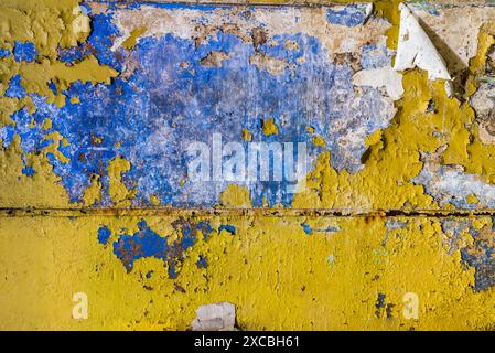 Texture d'un vieux mur bleu grunge coloré avec peinture jaune pelable Banque D'Images