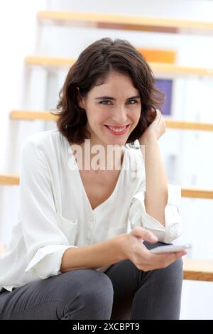 Femme assise sur un escalier et à l'aide de smart phone Banque D'Images