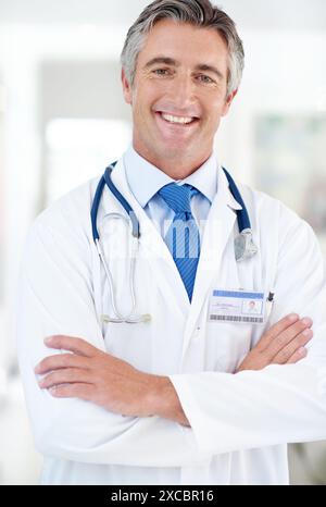 Heureux, médical et portrait de médecin avec les bras croisés à l'hôpital avec positif, confiant et fierté. Sourire, soins de santé et professionnel mature Banque D'Images