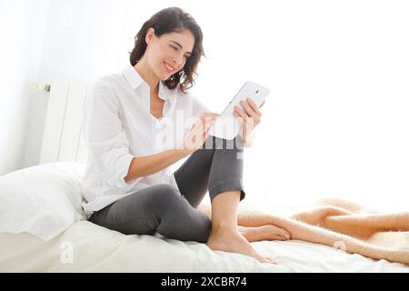 Woman using tablet computer and smiling Banque D'Images