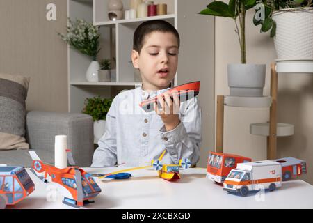 L'enfant fabrique de l'artisanat à partir de papier, de colle et de ciseaux. Créativité des enfants, loisirs intéressants Banque D'Images