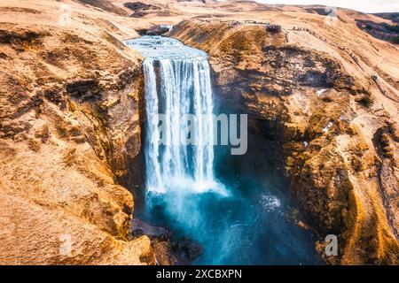Vue aérienne de la majestueuse puissante cascade Skogafoss coulant de falaise parmi la montagne sèche en automne au sud de l'Islande Banque D'Images