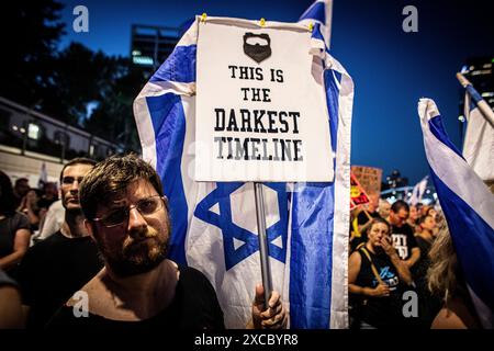 Tel Aviv, Israël. 15 juin 2024. Un manifestant tient une pancarte qui dit Òthis est le plus sombre timelineÓ lors d'une manifestation à tel Aviv, le samedi 15 juin 2024. Des dizaines de milliers de manifestants se sont rassemblés dans des dizaines de lieux à travers Israël samedi soir pour appeler à la fin de la guerre à Gaza pour un accord d’otages et de nouvelles élections quelques heures seulement après la nouvelle de huit soldats israéliens tués dans une explosion à Rafah samedi matin. Photo par Eyal Warshavsky. Crédit : Eyal Warshavsky/Alamy Live News Banque D'Images