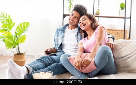 Couple détendu se relaxant sur le canapé tout en regardant la télévision Banque D'Images