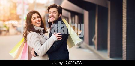 Jeune couple tenant des sacs à provisions dans la rue Banque D'Images