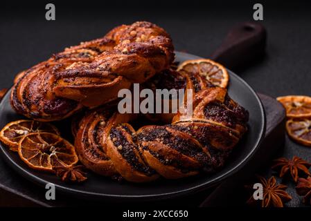 Délicieux petit pain cuit au four frais avec des graines de pavot et des baies en forme d'anneau sur un fond de béton foncé Banque D'Images