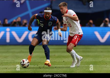 Hambourg, Allemagne. 16 juin 2024. Football : Championnat d'Europe, Pologne - pays-Bas, tour préliminaire, groupe d, jour de match 1, Volksparkstadion Hamburg, Memphis Depay des pays-Bas (l) et Taras Romanczuk de Pologne se battent pour le ballon. Crédit : Jens Büttner/dpa/Alamy Live News Banque D'Images