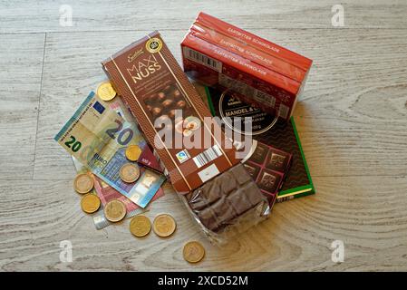 Image symbolique de l'inflation, de l'augmentation des prix des denrées alimentaires, des paquets de chocolat avec des billets de banque et des pièces de monnaie Banque D'Images