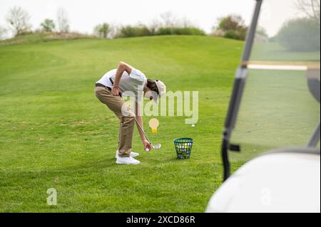 Jeune homme exerçant en jouant au golf et regardant concentré Banque D'Images