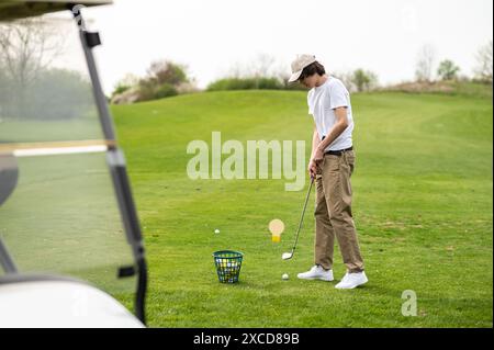 Jeune homme exerçant en jouant au golf et regardant concentré Banque D'Images