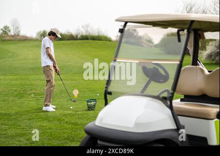 Jeune homme exerçant en jouant au golf et regardant concentré Banque D'Images