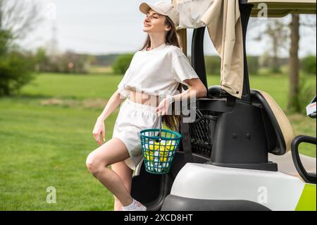 Femme active posant avec un équipement de golf près du véhicule à l'extérieur Banque D'Images