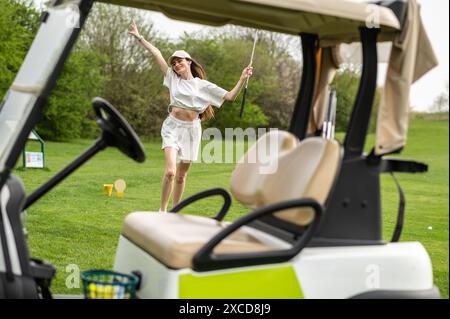 Femme active posant avec un équipement de golf près du véhicule à l'extérieur Banque D'Images