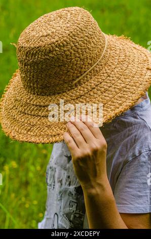 Femme en chemise blanche tenir le chapeau en bois couvert visage en flou naturel. Photo de haute qualité Banque D'Images
