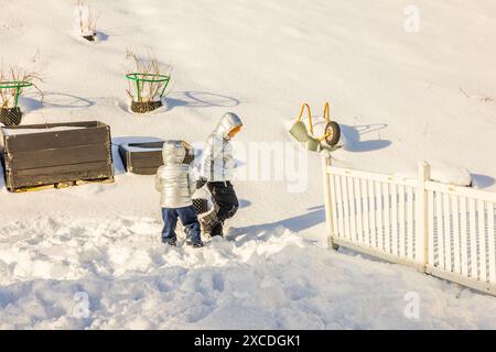 Belle vue hivernale sur le jardin d'une villa privée avec deux garçons jouant dans la neige. Suède. Banque D'Images