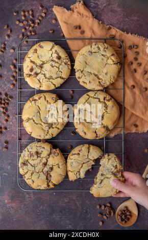 Biscuits fraîchement cuits sur grille de refroidissement avec la main de prise de cookie Banque D'Images