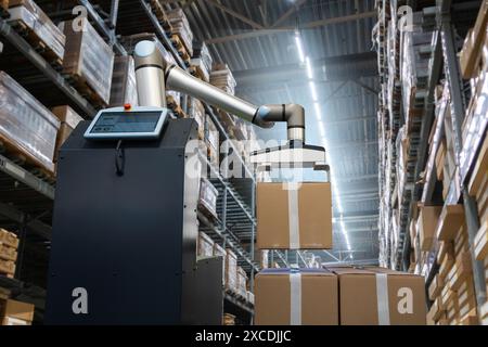 Le bras robotisé déplace les boîtes dans un entrepôt automatique. Banque D'Images