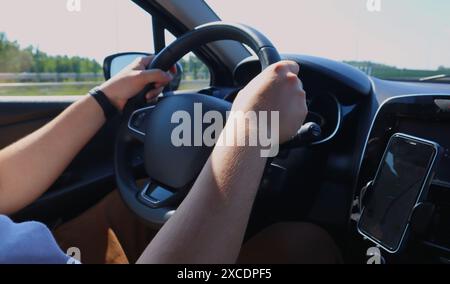 Homme conduisant une voiture, naviguant, les mains sur le volant Banque D'Images