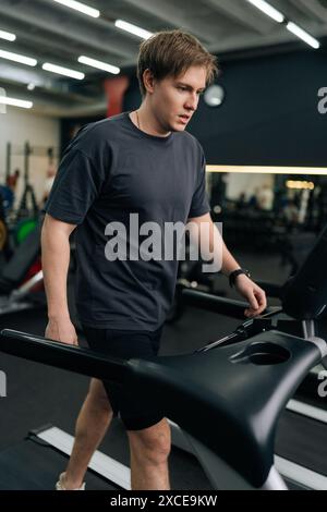 Plan vertical du coureur débutant masculin courant sur le tapis roulant, l'exercice de finition et éteint la machine d'entraînement. Sportif athlétique se reposant après Banque D'Images