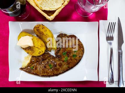 Savoureux foie de veau rôti avec pommes de terre cuites à l'assiette, plat espagnol Banque D'Images