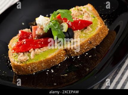 Assiette avec sandwich au thon en conserve, guacamole, poivre, tomate, olives,Arugula et feta Banque D'Images