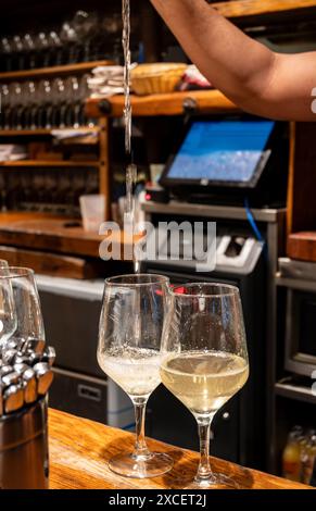 Versement spécial de txakoli ou chacolí vin blanc légèrement mousseux très sec dans des verres, produit dans le pays basque espagnol dans le bar pinchos typique Banque D'Images