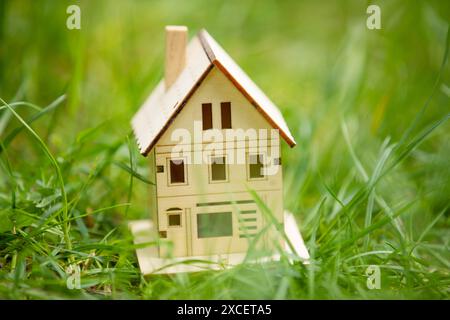 petite maison de jouet en bois, modèle du présent en vert brillant gazon de printemps mise au point sélective. nouvelle construction de maison et concept de vente d'achat Banque D'Images