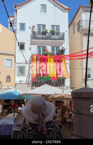 Touriste dans la rue Alfama à Lisbonne, Portugal, pendant les festivités populaires des Saints, regardant un bâtiment avec des décorations colorées typiques Banque D'Images