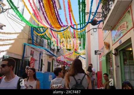 Les gens marchant dans les rues d'Alfama pendant les festivités populaires des Saints à Lisbonne, Portugal, avec des décorations de rue colorées typiques Banque D'Images