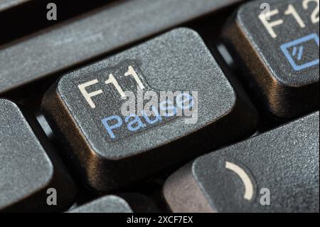 Macro, gros plan extrême détail d'une touche pause F11 sur un clavier d'ordinateur portable moderne, personne, pas de gens. Pause prendre une pause dans les activités de travail Banque D'Images