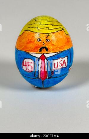 Dessin de dessin animé sur oeuf montre le 45e président «oeufs» portant une combinaison de prison orange et faisant un visage surpris, sur un fond blanc. Banque D'Images