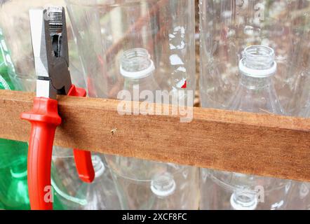 Mur écologique construit à partir de la réutilisation de bouteilles en plastique colorées d'une pépinière de semis dans un jardin urbain, communautaire et éducatif de la ville. Banque D'Images