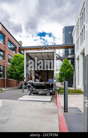 Semi-camion de plate-forme de cabine de jour de service moyen industriel avec remorque de caisse pour les marchandises locales debout avec porte arrière ouverte sur la construction urbaine de rue Banque D'Images