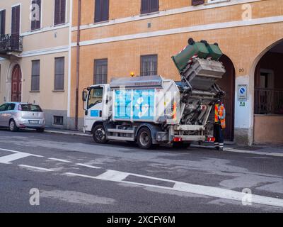 Cremona, Italie - 10 juin 2024 camion à ordures ramasse les poubelles dans une zone urbaine avec un homme à ordures debout à côté Banque D'Images