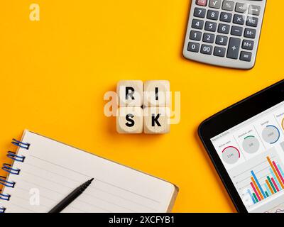 Concept de risque financier commercial. Le mot risque sur des cubes en bois sur fond jaune de bureau. Banque D'Images