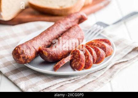 Saucisse de salami fumé tranchée sur une assiette. Banque D'Images