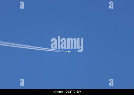 Avion en vol avec traînée de vapeur ou traînée de traînée dans un ciel bleu, Angleterre, Royaume-Uni Banque D'Images