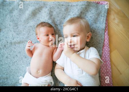 Portrait de mignon petit bébé allongé sur le lit à côté de son frère aîné. Banque D'Images