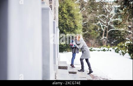 Mère emmenant sa fille à l'école, disant au revoir devant le bâtiment de l'école, se dirigeant vers le travail. Banque D'Images