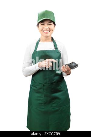 Vendeur asiatique porter tablier vert et chapeau vert souriant avec main tenant le doigt de lecteur de carte pointe isolé sur blanc Banque D'Images
