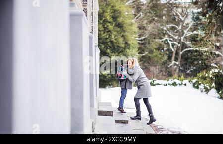 Mère emmenant sa fille à l'école, disant au revoir devant le bâtiment de l'école, se dirigeant vers le travail. Concept d'équilibre entre vie professionnelle et vie privée pour les femmes. Banque D'Images