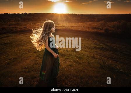 Profil de belle jeune fille debout sur la colline au coucher du soleil Banque D'Images