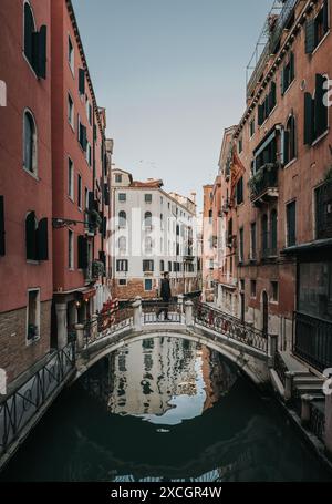 Homme marchant à travers le pont de pierre sur le canal à Venise, Italie. Banque D'Images