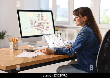 Femme travaillant avec la carte cadastrale sur les ordinateurs à table dans le bureau Banque D'Images