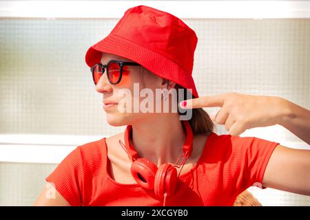 Une jeune femme portant des lunettes de soleil est assise, pointant son doigt sur le côté. Banque D'Images